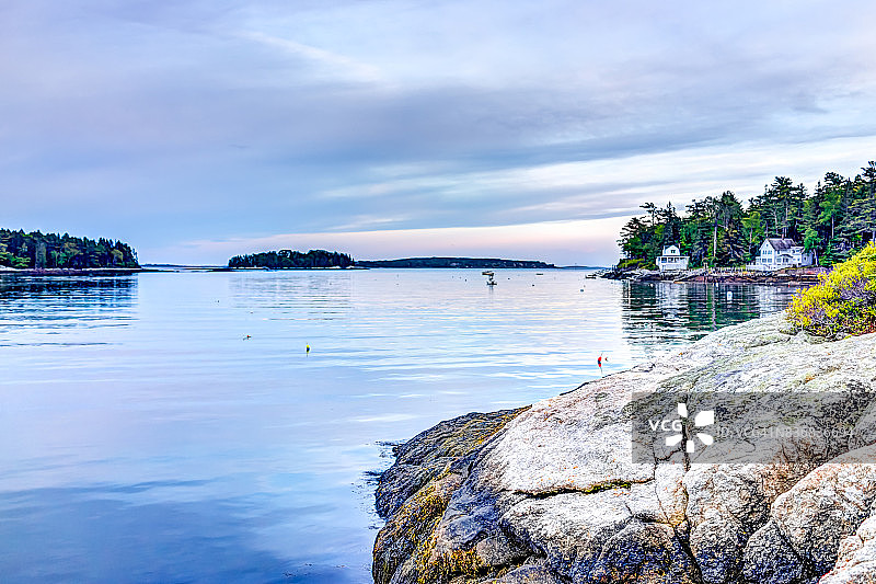 缅因州布斯贝港小村庄的傍晚日落，岩石海岸和房屋图片素材