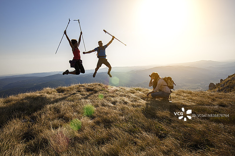 年轻情侣在山顶开心跳跃图片素材