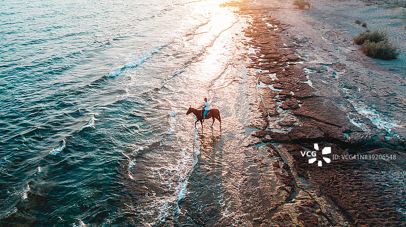 男子在日落时分的海滩上骑马图片素材