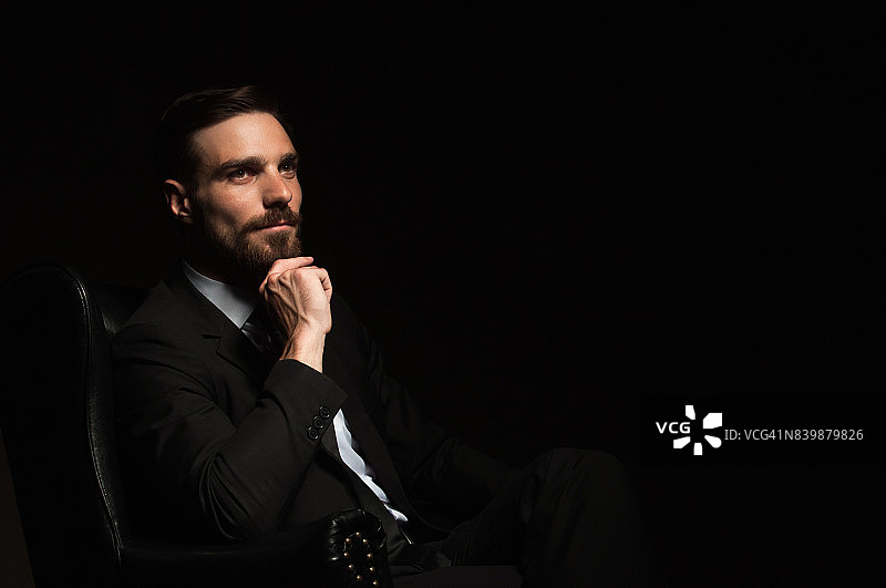 自信优雅的男士坐在扶手椅上图片素材
