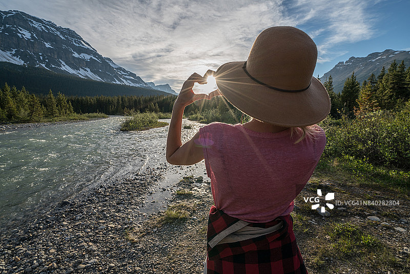 年轻女子在山景前用手指比心图片素材