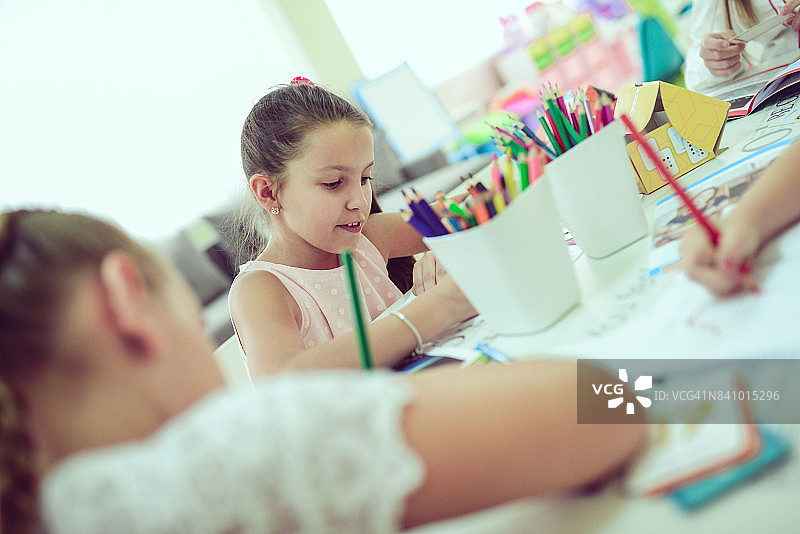 在幼儿园教室里素描和绘画的微笑小女孩图片素材