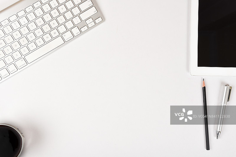 白色桌面，配有电脑键盘、平板电脑和咖啡杯，留白图片素材