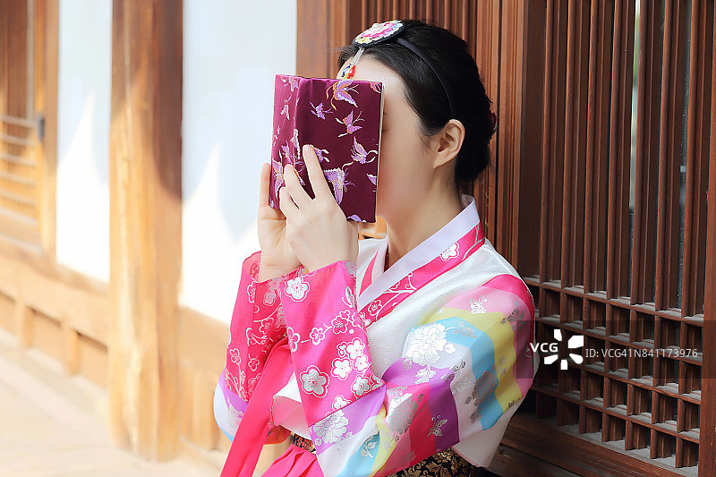 用书遮住脸的传统韩国女人图片素材