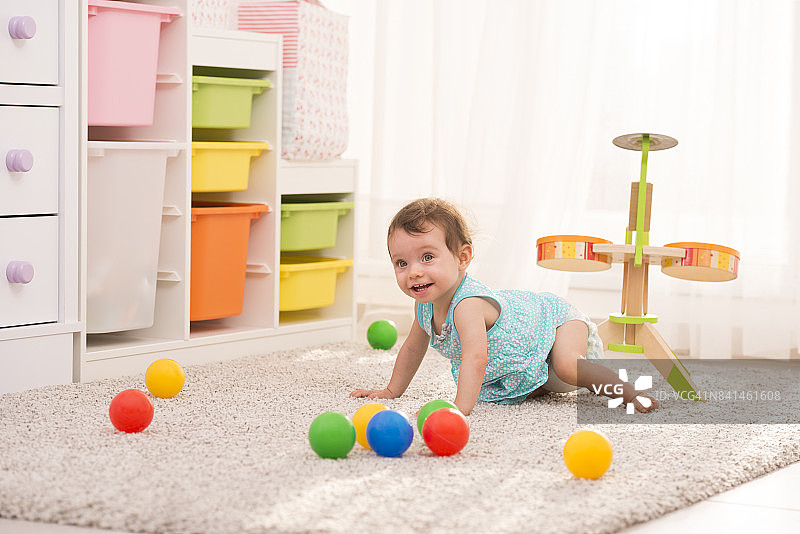 可爱的女宝宝在儿童房玩彩色球图片素材