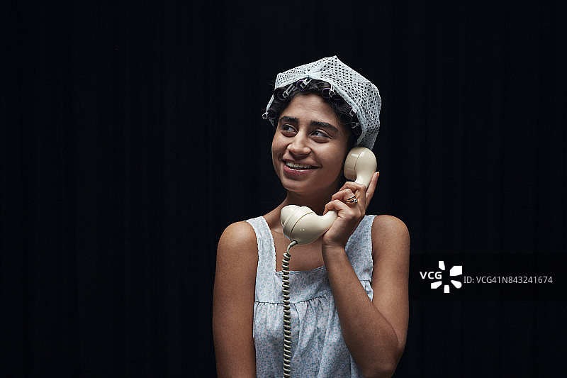 戴复古发网的年轻女人拿着老式座机图片素材