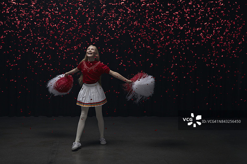 年轻啦啦队员仰望红色纸屑飘落图片素材