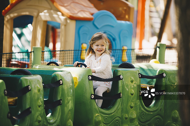 年轻女孩在游乐园的火车上微笑图片素材