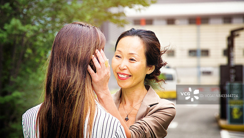 日本中年母亲在停车场迎接女儿图片素材