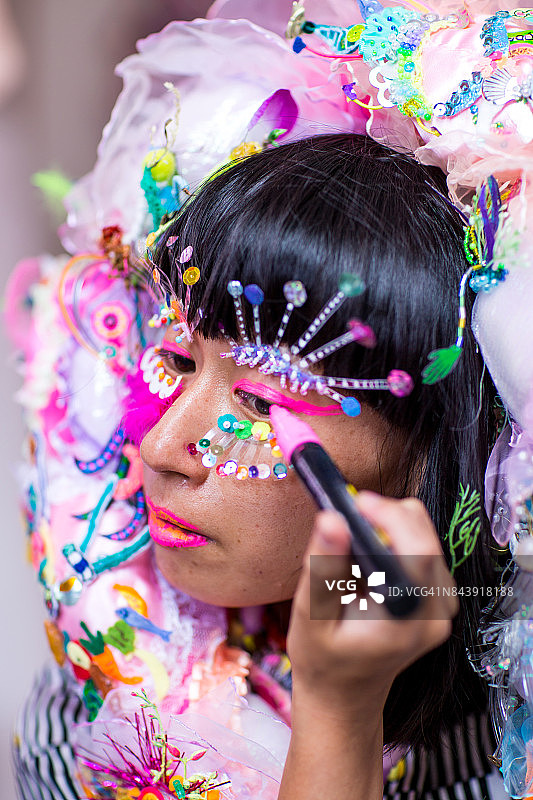 一位女纺织艺术家正在准备和装饰一件色彩鲜艳的服装并化妆图片素材