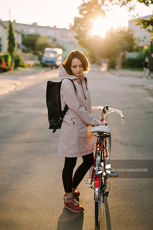 穿着粉色雨衣在城市里行走的背包女人图片素材