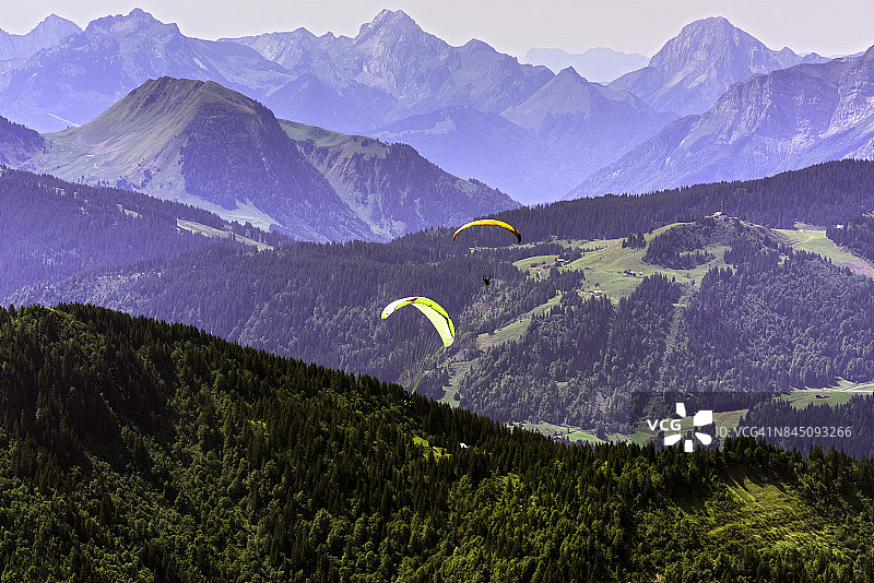 在法国上萨瓦省大博尔南村附近法国阿尔卑斯山上空飞行的滑翔伞图片素材