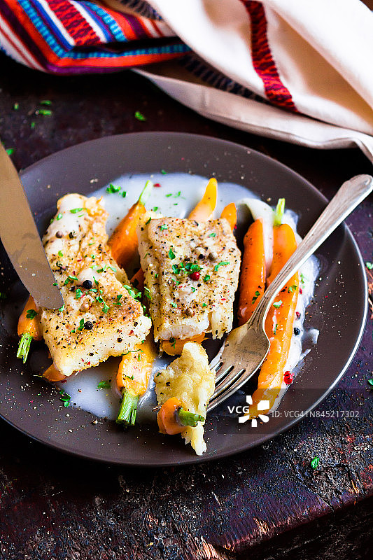 烤白鱼片配奶油酱和小胡萝卜，选择性聚焦图片素材