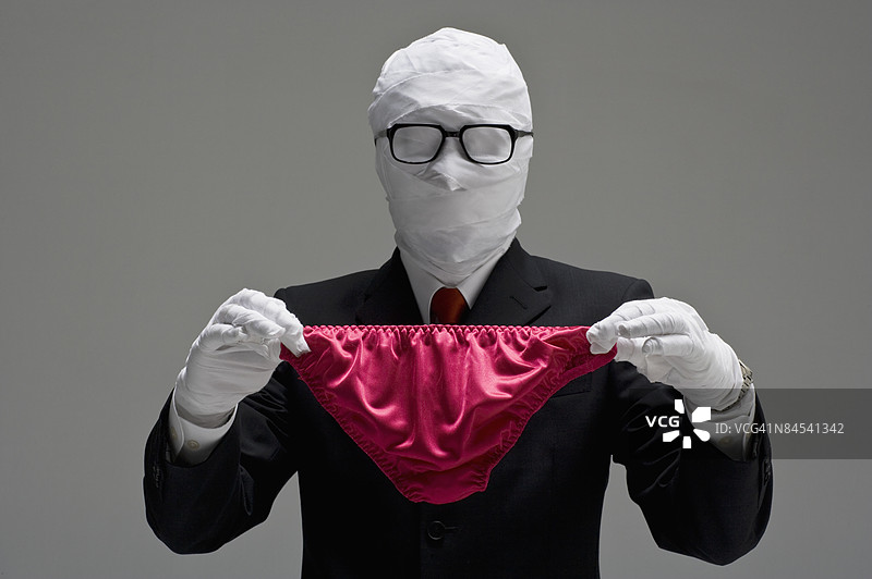 包扎着的商人手持内裤，摄影棚拍摄图片素材