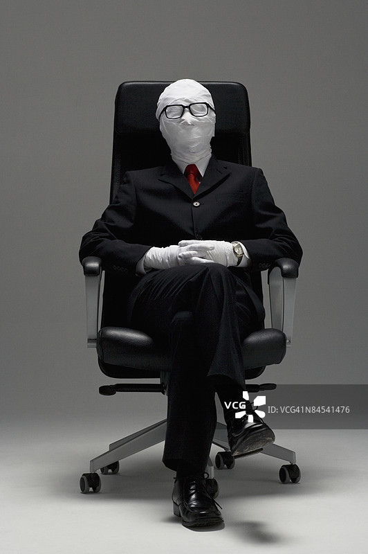 坐在椅子上双腿交叉的商人裹着绷带，摄影棚拍摄图片素材