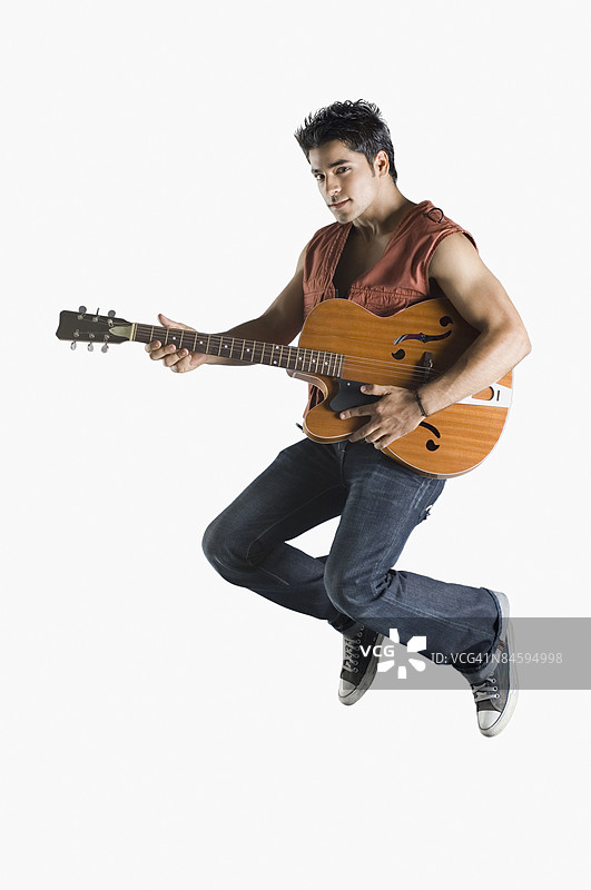 年轻男子弹吉他并跳跃的肖像图片素材