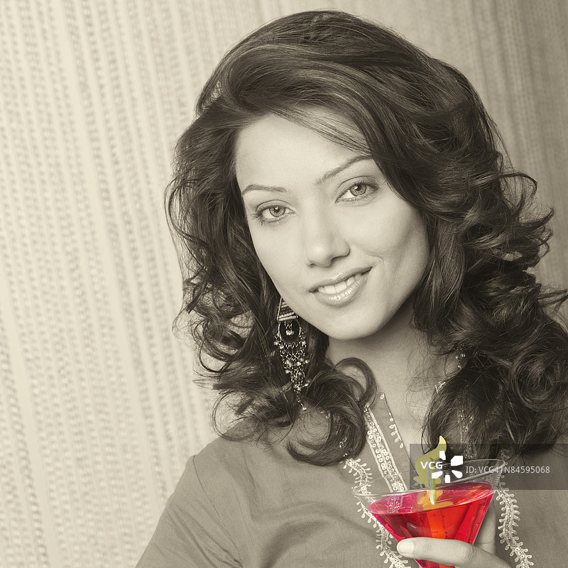 年轻女性微笑着手持一杯马提尼酒的肖像图片素材