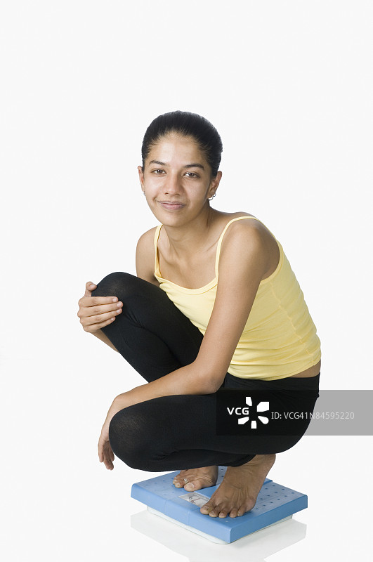 年轻女性站在体重秤上图片素材
