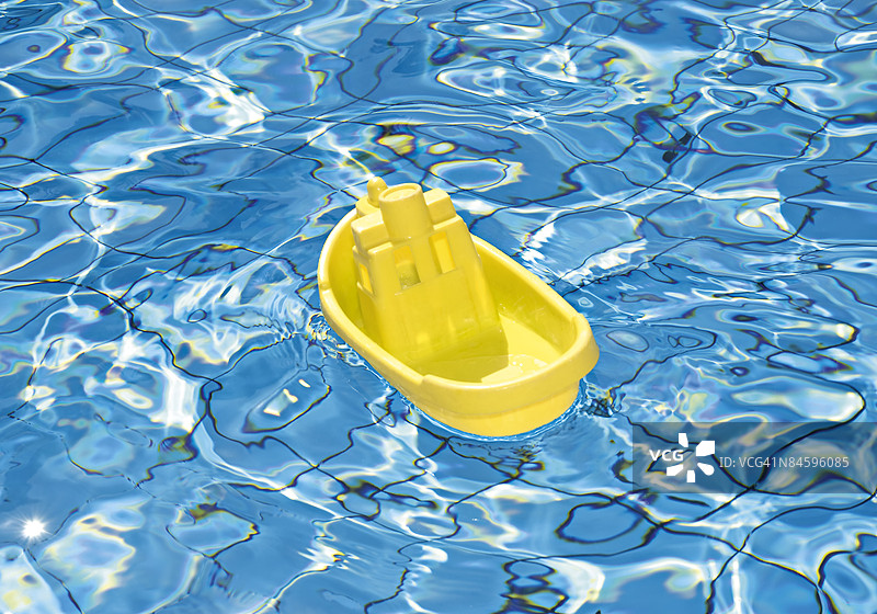 黄色玩具船在泳池中漂浮图片素材