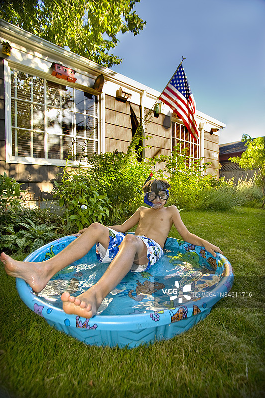 男孩戴着潜水镜躺在浅水池里图片素材