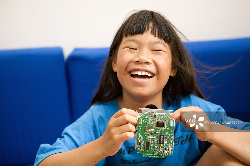 一个女孩手持电路板并微笑的肖像图片素材