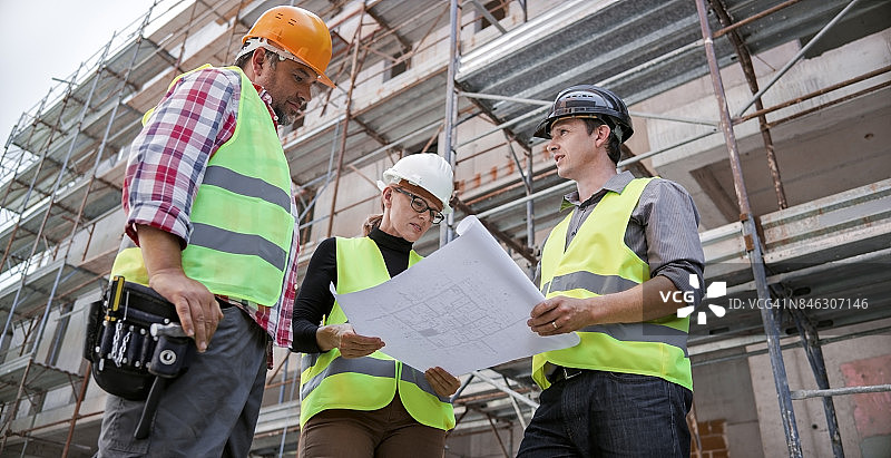 工程师、建筑师和工头在建筑工地交谈并查看图纸图片素材