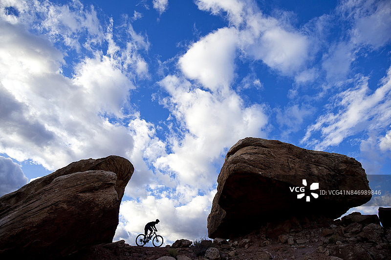 傍晚，男子在美国犹他州莫阿布的热门小道上骑山地自行车图片素材