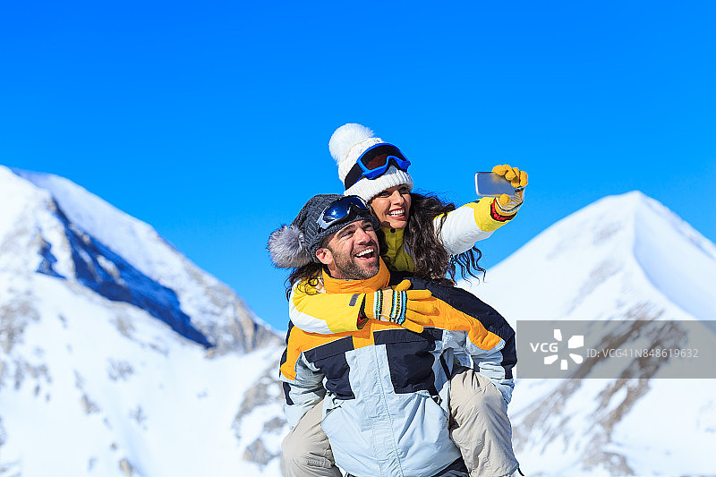 年轻滑雪情侣在雪山顶上自拍图片素材