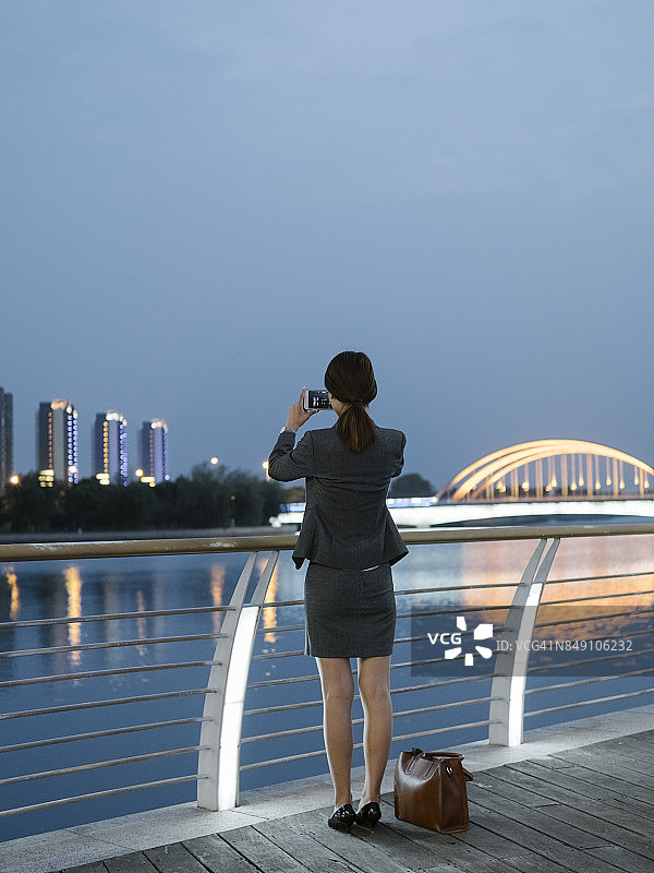 穿着工作服拍摄美丽风景的后视图女人图片素材