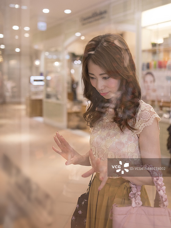 美女隔着商店橱窗看商品图片素材