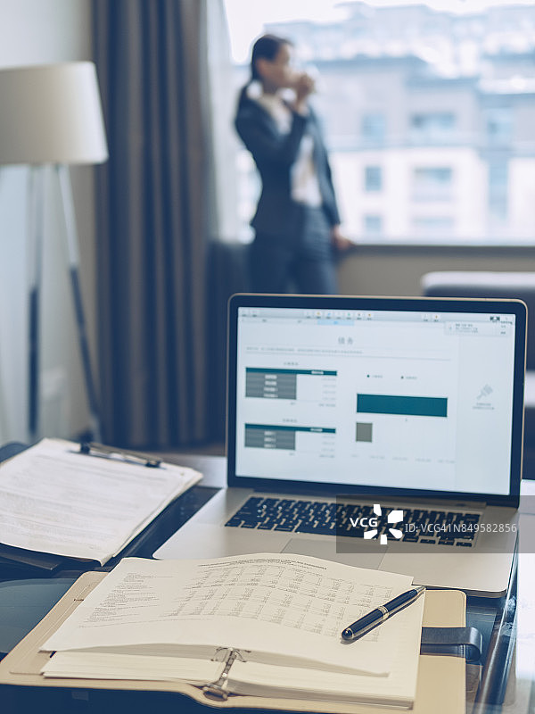 办公桌特写，模糊的商务女人在窗边喝水图片素材