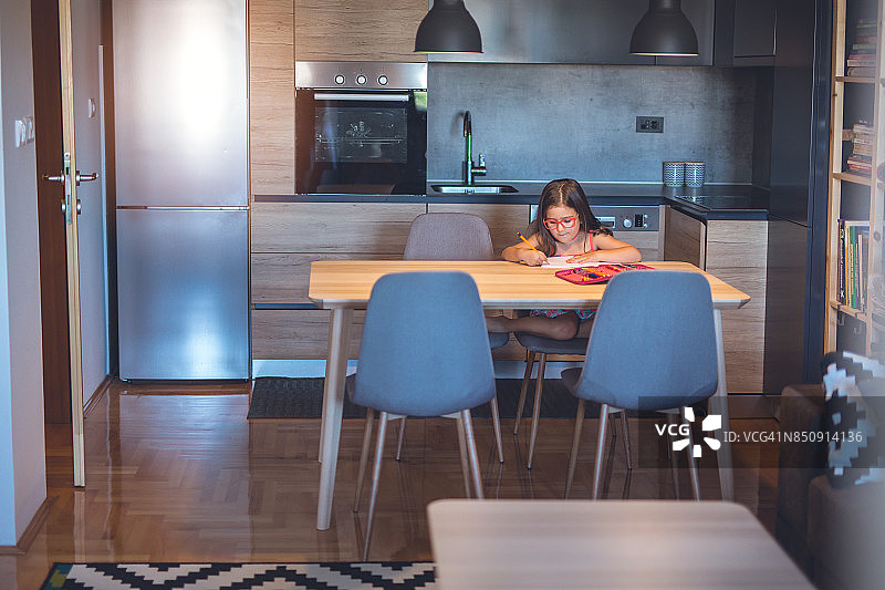 在厨房做作业的可爱小女孩图片素材