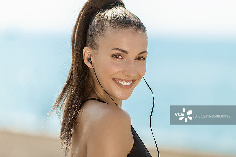 在海滩听音乐的运动型女人图片素材