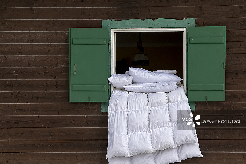 小木屋绿色窗台上晾晒羽绒被图片素材
