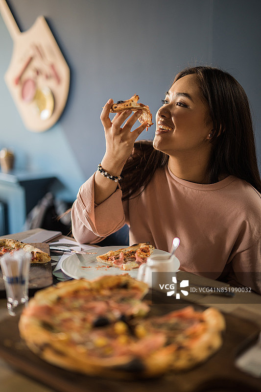 快乐的韩国女人在餐厅吃午餐披萨图片素材