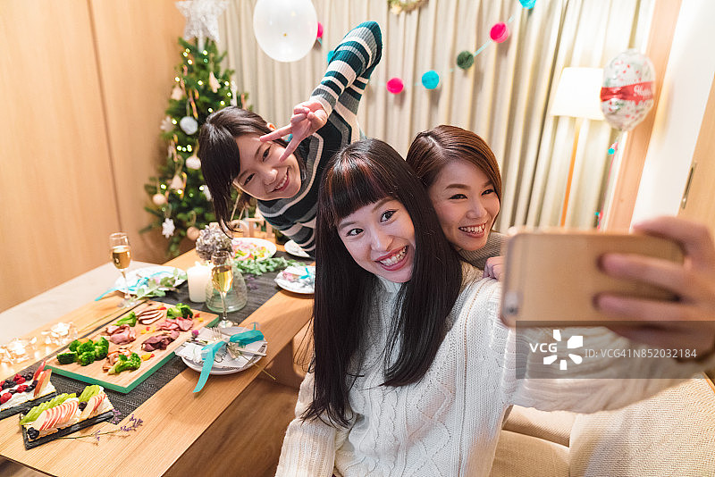 三位年轻女性朋友庆祝圣诞节并自拍图片素材
