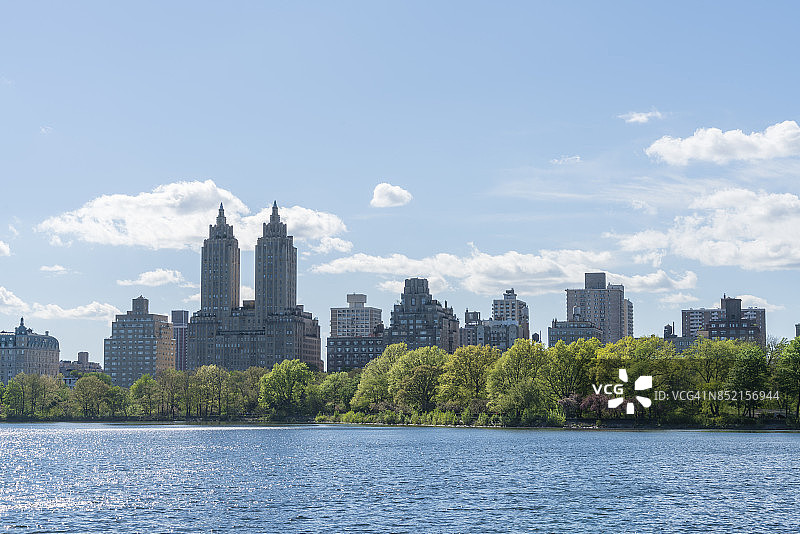 阳光照耀下的纽约中央公园水库波光粼粼，绿树和中央公园西历史街区图片素材