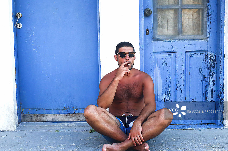 年轻帅哥坐在户外吸烟图片素材