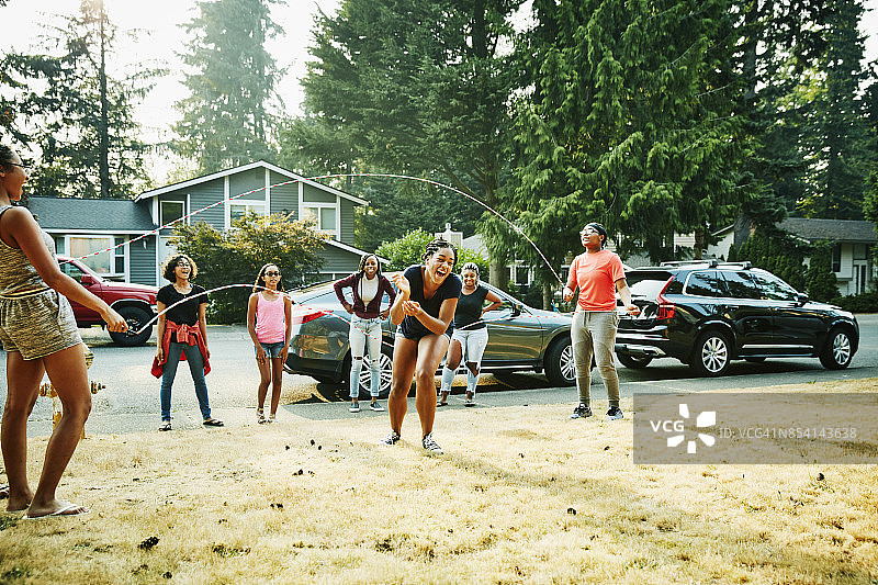 在夏日傍晚与朋友一起跳双摇跳绳的年轻女子图片素材