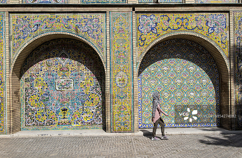 一名女子走过伊朗德黑兰古列斯坦宫的瓷砖墙图片素材