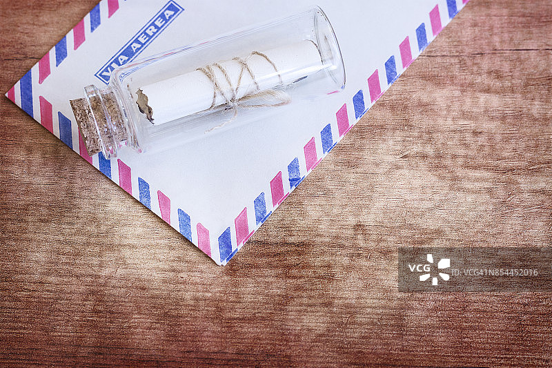 木桌背景上的漂流瓶和信封，高角度视图和复制空间图片素材