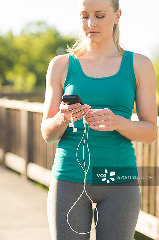 跑步前选择音乐的金发慢跑者图片素材