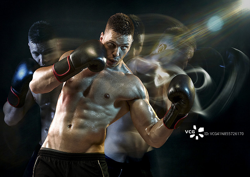 拳击手戴着黑色手套快速出拳，在工作室背景中进行长曝光拍摄图片素材