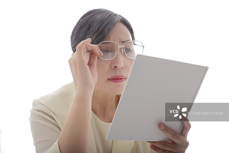 阅读书籍的中年妇女，老花眼，眯着眼睛图片素材