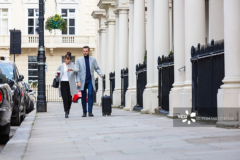 走在城市街道上的优雅情侣，男人提着手提箱图片素材
