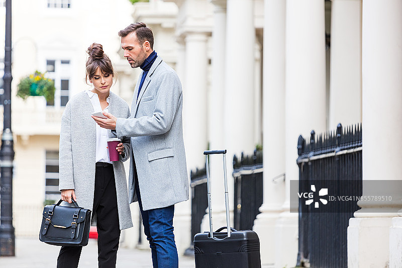 优雅情侣在城市街道上，男人拿着手机图片素材