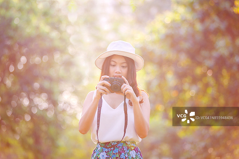 在樱花公园里微笑的美丽亚洲女人，完美笑容，看着屏幕相机图片素材