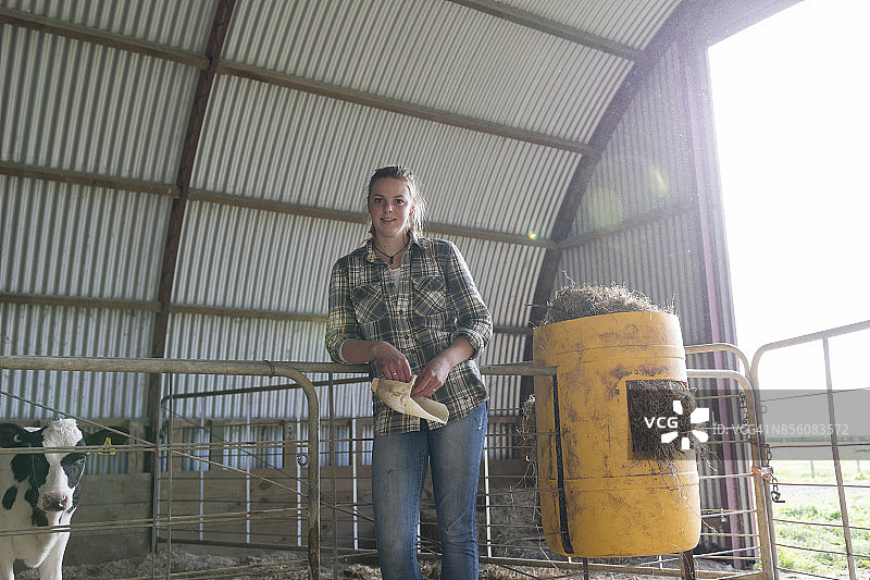 倚靠在谷仓内大门上的农场女孩图片素材