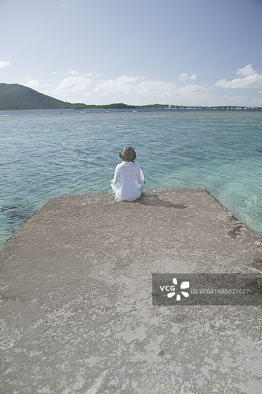 女人坐在岩石上俯瞰热带海洋图片素材