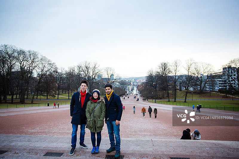 冬季奥斯陆，三位朋友在皇宫台阶上的合影图片素材